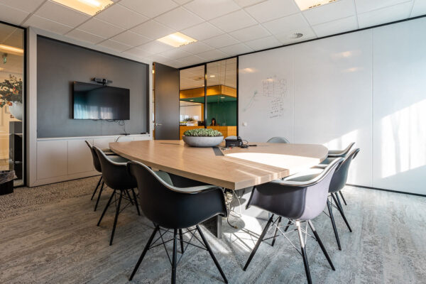 Moderne vergaderruimte in Rivium Quadrant met houten tafel, zwarte stoelen, flatscreen en whiteboardwand.
